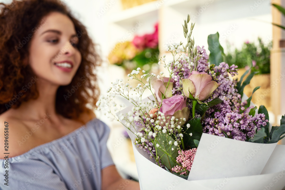 Creative floristic design. Selective focus of a beautiful flower being in hands of a cheerful delighted woman