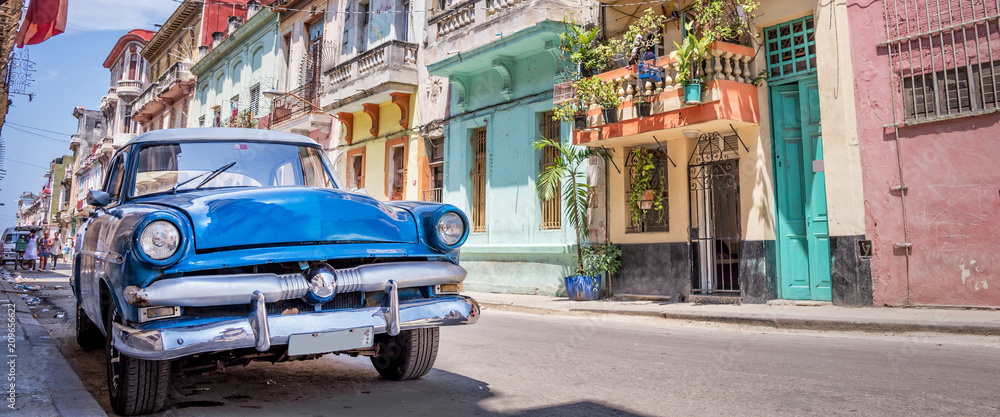Vintage classic american blue car in a colorful street of Havana, Cuba web banner. Panoramic cuban travel and tourism photo