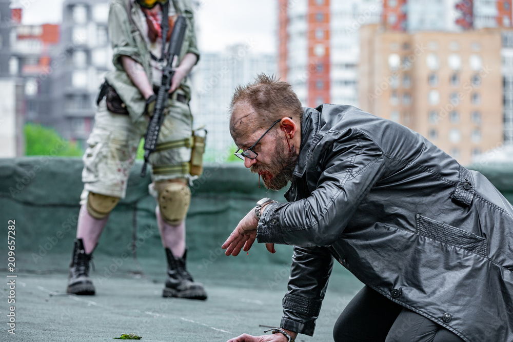 Naklejka premium Woman soldier, spy agent killer or police woman with a gun in her hand holding at gunpoint a man lying on the ground