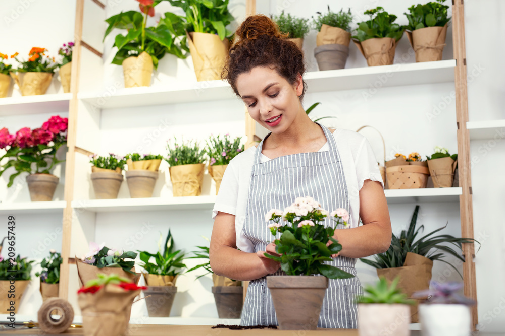 Shop assistant. Pleasant attractive woman selling flowers while working as a shop assistant
