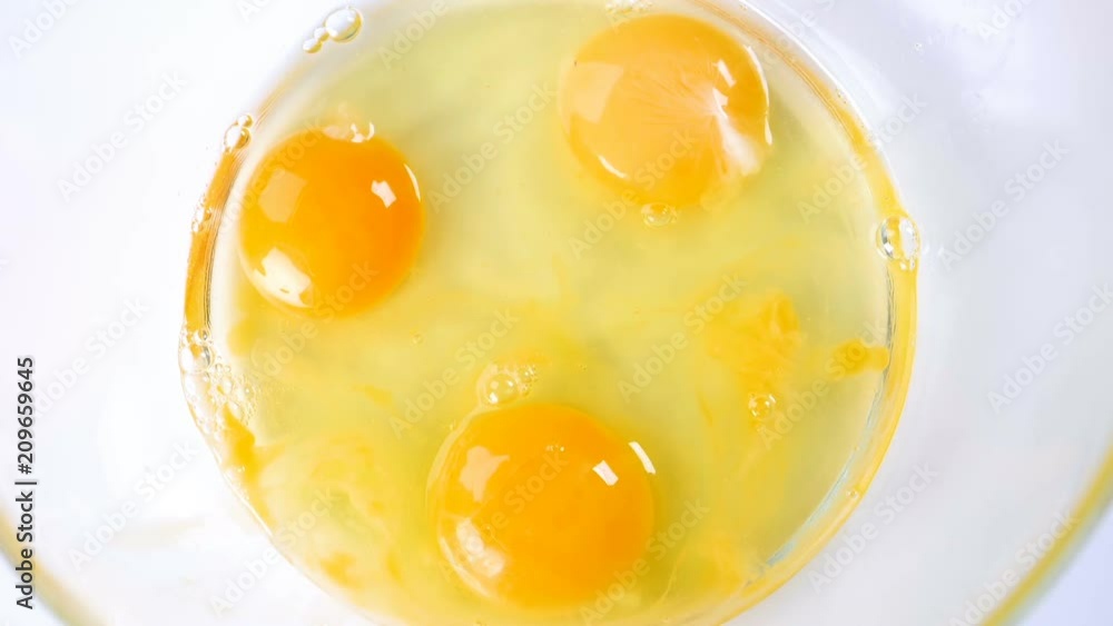 Breaking eggs in a glass bowl. Fresh organic eggs falling into bowl. Preparing ingredients for baking. Slow motion footage. Breaking eggs in a glass bowl. Fresh organic eggs falling into bowl. Preparing ingredients for baking. Slow motion footage.