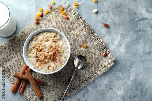 Quadro su tela Bowl with tasty oatmeal and cinnamon on grey textured background