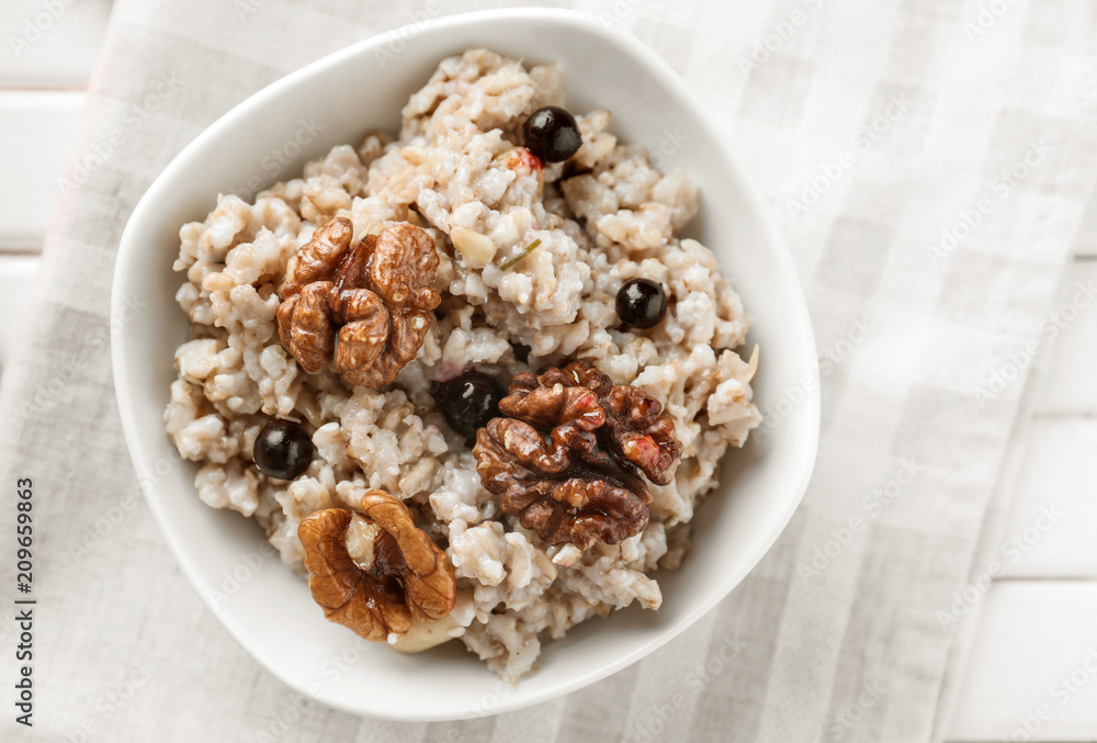 Bowl with tasty oatmeal, berries and nuts on white table Bowl with tasty oatmeal, berries and nuts on white table