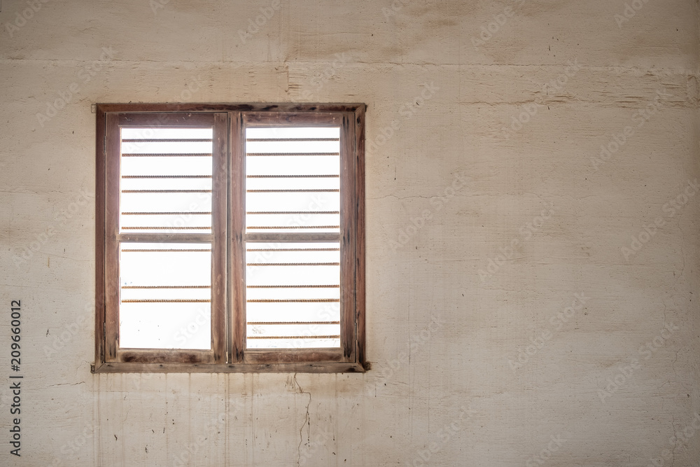 A glassless, barred window in the wall of a room in an abandoned, derelict building with stained walls.