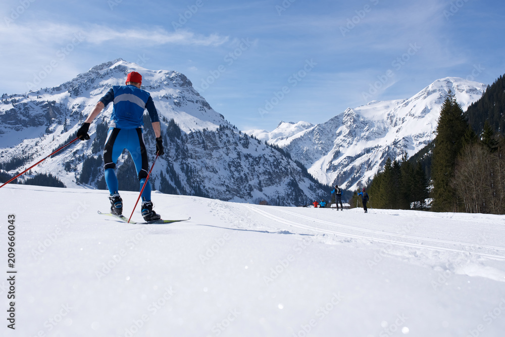 Skilangläufer vor Alpenbergen im Winter beim Skifahren6