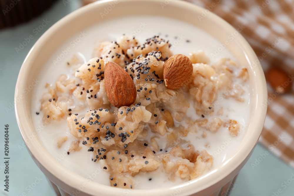 Tasty oatmeal with milk and nuts in bowl on table, closeup Tasty oatmeal with milk and nuts in bowl on table, closeup