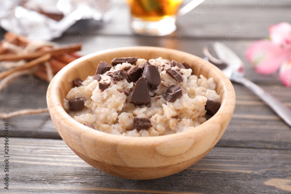 Bowl with tasty oatmeal and chocolate on wooden background Bowl with tasty oatmeal and chocolate on wooden background