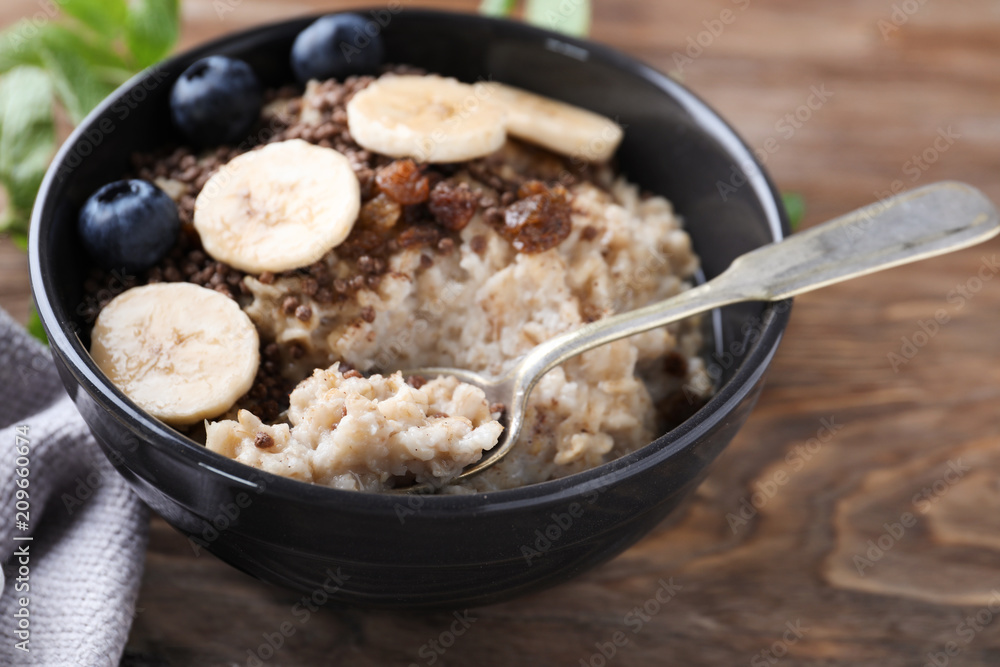 Tasty oatmeal with banana and blueberries in bowl on table Tasty oatmeal with banana and blueberries in bowl on table