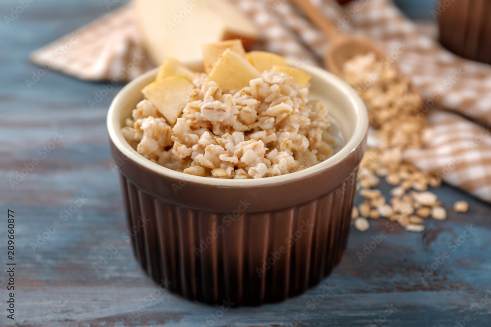 Bowl with tasty oatmeal on wooden table