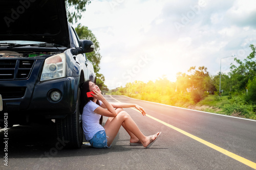 Asia woman have a problem about her car.beautiful lady calling to insurance to help and fix her broken car stop near the road during her travel on vacation.