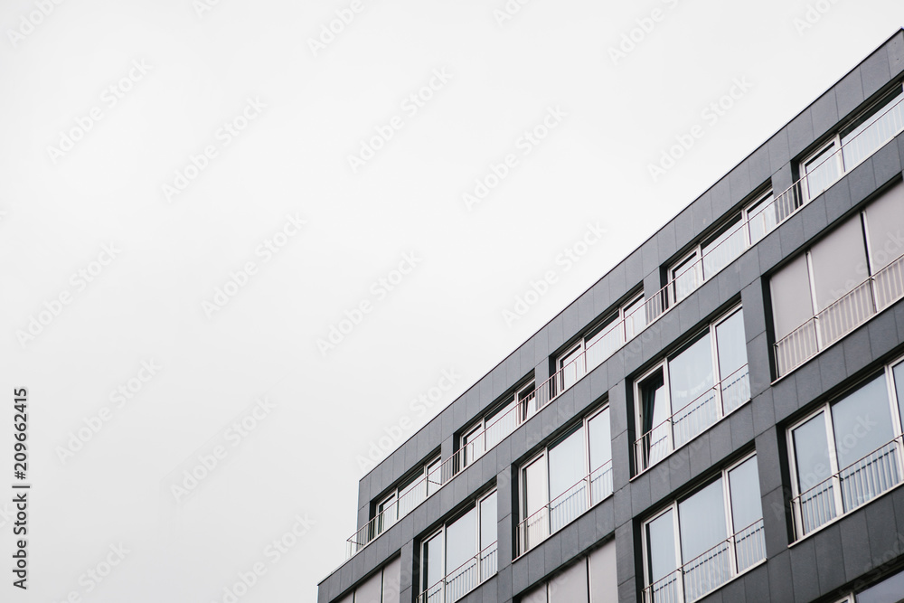 Fototapeta premium The corner of the building with many windows against the gray sky