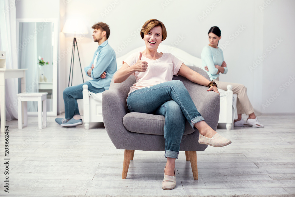 Great job. Delighted joyful mother in law sitting in the armchair while showing thumbs up Great job. Delighted joyful mother in law sitting in the armchair while showing thumbs up