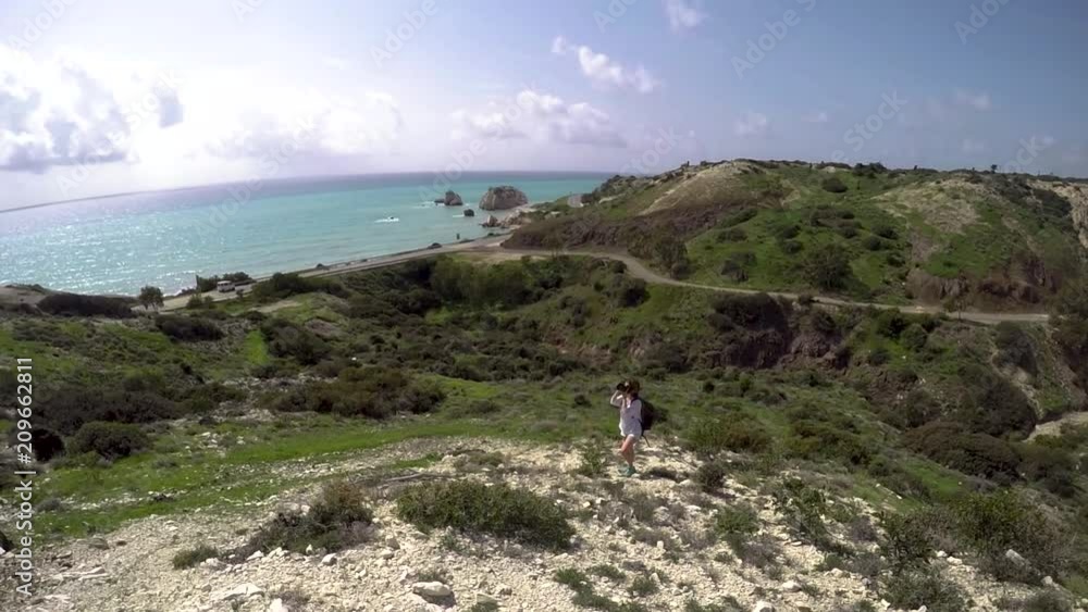 Young woman professional photographer taking picture of the landscape. Rocky mountains with a sea view. Young woman professional photographer taking picture of the landscape. Rocky mountains with a sea view.
