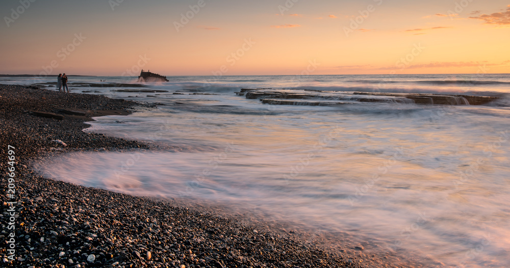 Obraz premium Rocky seashore with wavy ocean and waves crashing on the rocks
