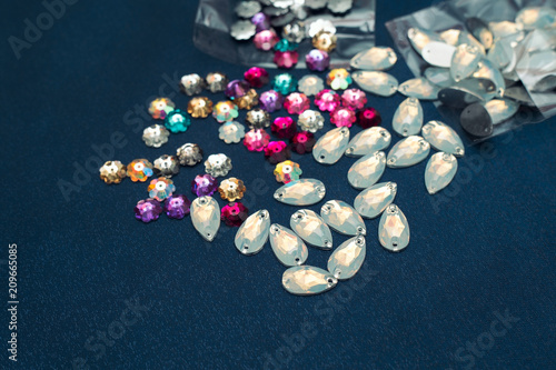 Scattering beads and glass leaves. Rhinestones embroidery. Beads on fabric. Materials for craft and creative work.