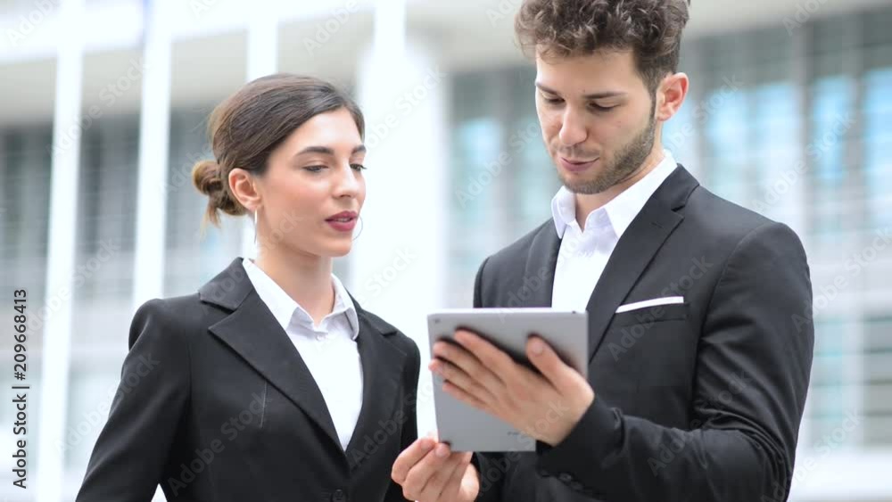 Couple of business people using a tablet outdoor Couple of business people using a tablet outdoor