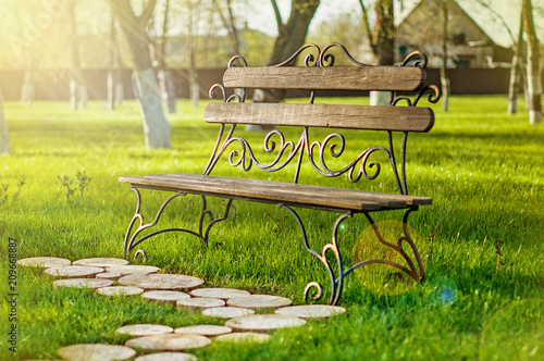 Wooden bench with iron forging pattern in a park on sunny day. photo