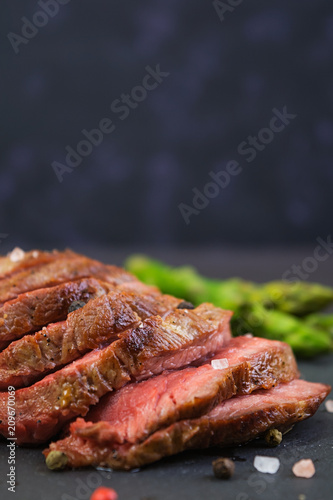 Grilled beef steak and asparagus on wooden background