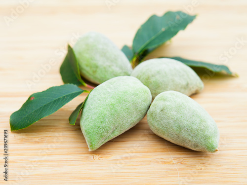 Young Green Alond Nuts in Shells on Wooden Background. photo