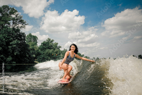 Young attractive active woman riding on the wakeboard