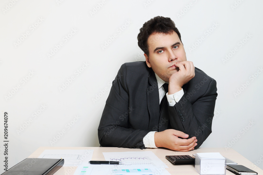 Businessman in suit sits at table with notebook, documents, paper Businessman in suit sits at table with notebook, documents, paper