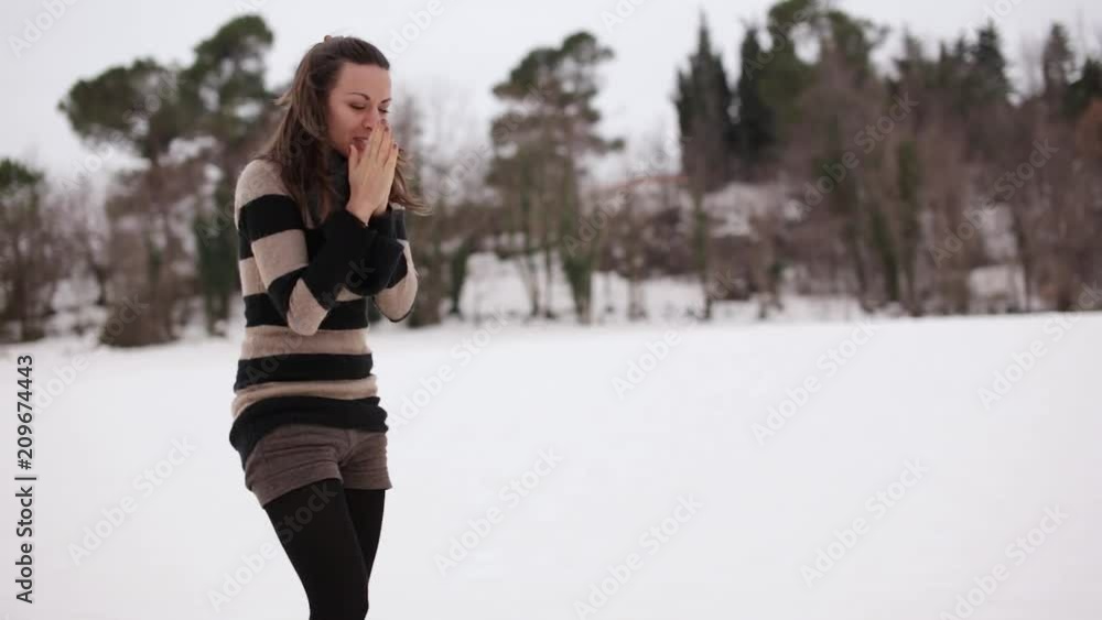 Young pretty smiling woman heats her hands in a snowy environment Young pretty smiling woman heats her hands in a snowy environment
