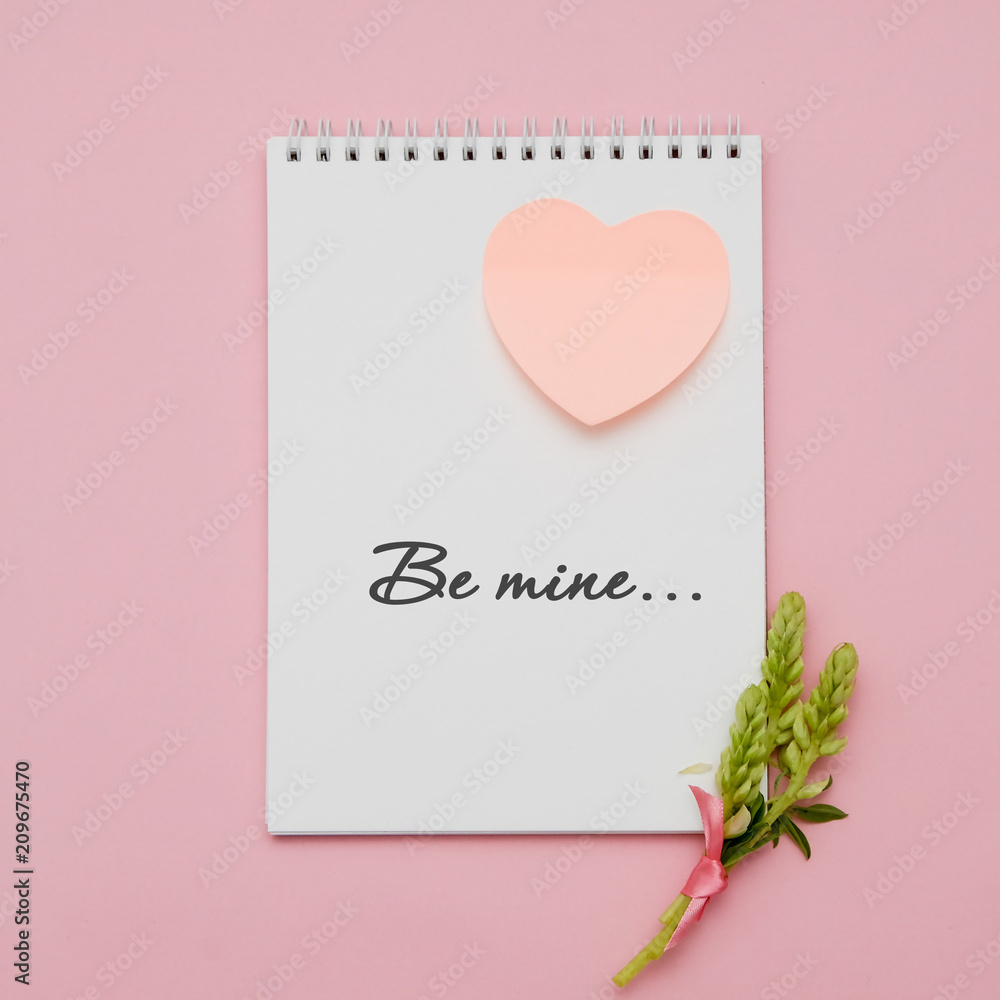 Composition with flowers and notebook on pink background. Flat lay. hand writing - be mine...