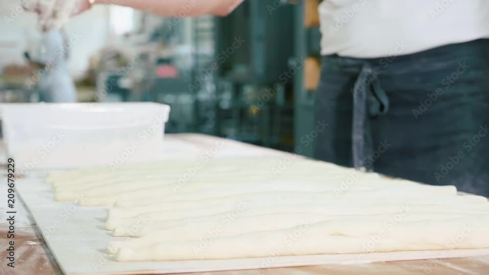 Professional baker pouring a flour on raw bread before baking at bakery kitchen Professional baker pouring a flour on raw bread before baking at bakery kitchen