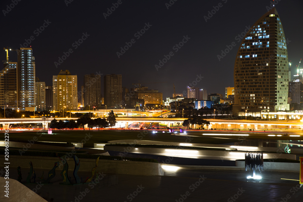 Night view of the center of Baku. The movement of cars through the night city. Skyscrapers, high-rise buildings and automobile interchanges. Republic of Azerbaijan