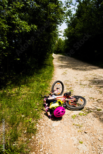 Little girl falling off her bicycle. Family, education, recreation and sport concept.