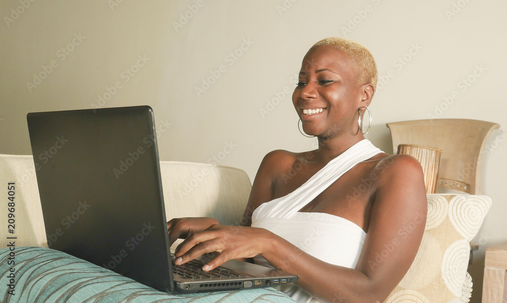 young beautiful and happy black afro American woman smiling excited having fun on internet using social media on laptop computer at home living room young beautiful and happy black afro American woman smiling excited having fun on internet using social media on laptop computer at home living room
