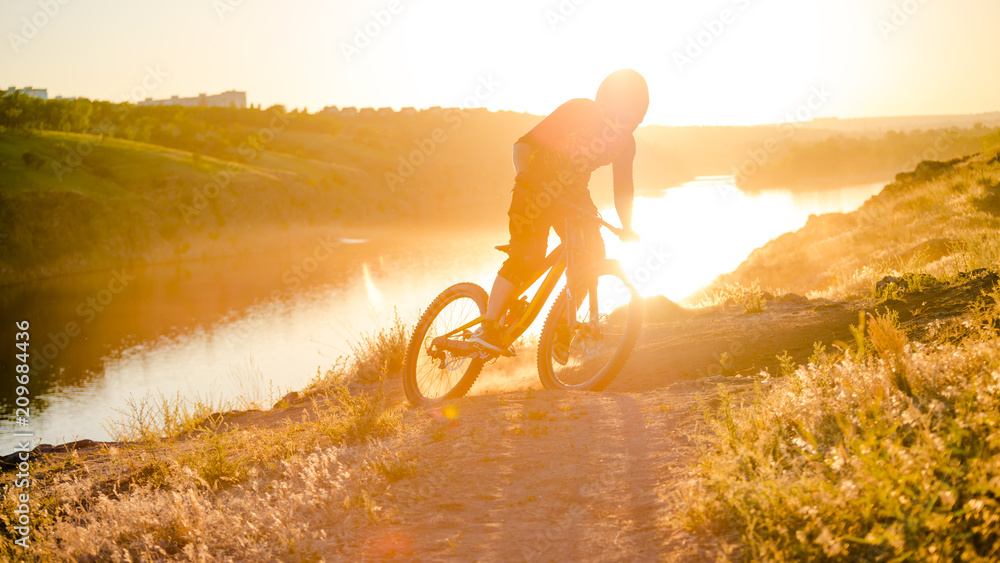 Fototapeta premium Cyclist Riding the Mountain Bike on the Summer Rocky Trail at the Evening. Extreme Sport and Enduro Cycling Concept.