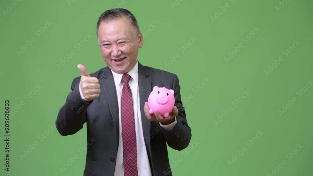 Mature Japanese businessman holding piggy bank Mature Japanese businessman holding piggy bank