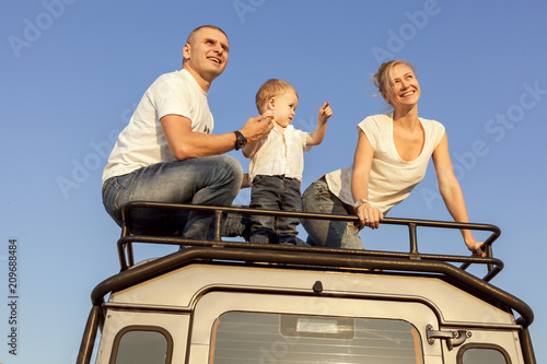 Portrait of a young family with a baby on the roof of a car. © Petro