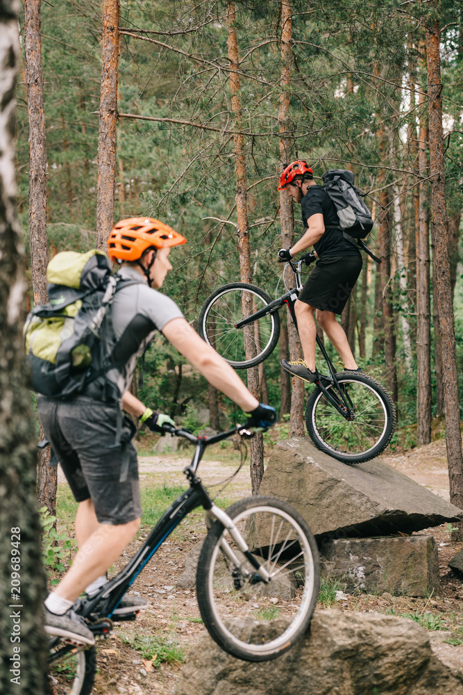 young trial bikers having fun in pine forest