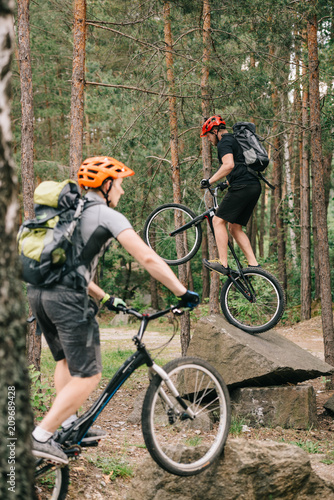 young trial bikers having fun in pine forest