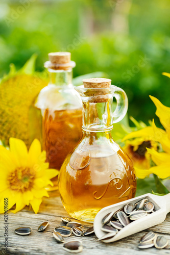 Closeup photo of sunflower oil with seeds on wooden background in the garden
