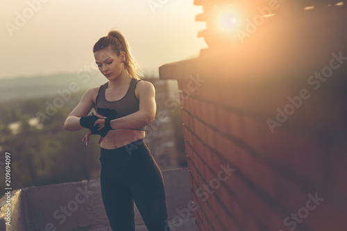 Billede på lærred Woman wrapping hands with bandages before workout