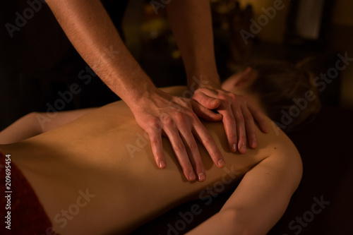 Young woman enjoying massage at spa centre. Warm romantic illumination. Relaxation, healthcare, harmony and beauty concept