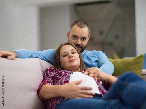 young pregnant couple relaxing on sofa