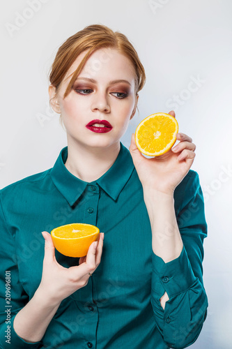 Sexy redhead young woman holding oranges halves