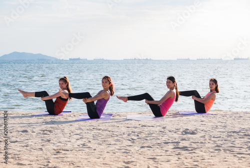 Yoga class at sea beach in evening ,Group of people doing Half Boat with clam relax emotion at beach,Meditation pose,Wellness and Healthy balance lifestyle.