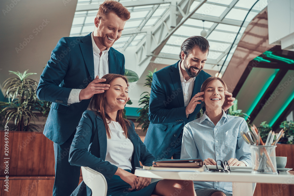 Two men massage heads of two women in office. Two men massage heads of two women in office.