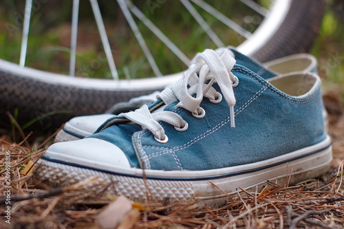 blue sneakers in a forest close-up on old dry needles, on a bicycle background. bike tour in the woods.