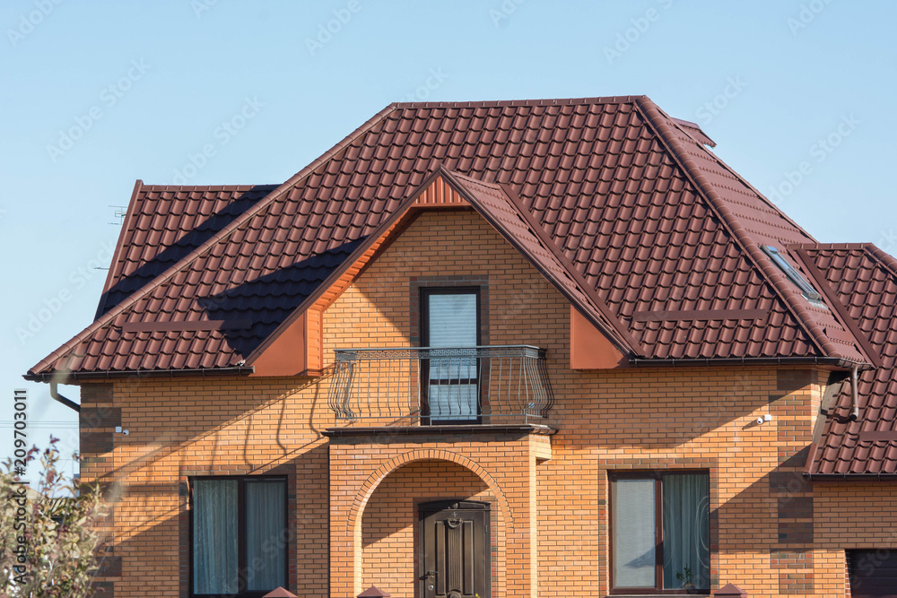 Brick house with balcony, multilevel roof and attic skylights