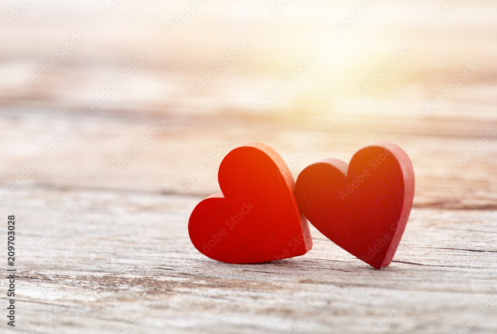 Two red hearts on wooden background in sunset Two red hearts on wooden background in sunset