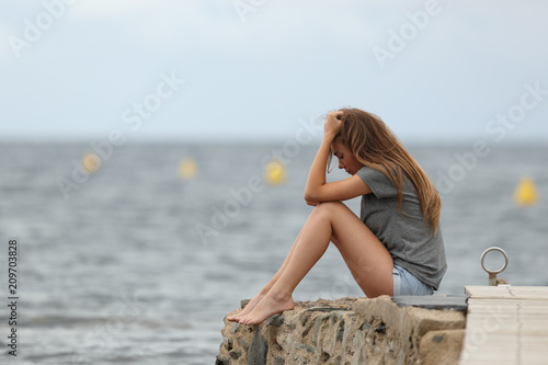 Sad teen alone with ocean in the background