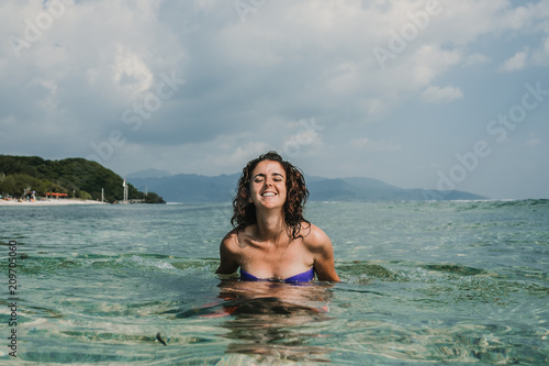 Beautiful woman on vacation in the gili islands enjoying at the lonely beach with turquoise blue water, relaxing, sunbathing and playing in the water. Travel photography.