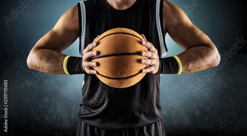 Basketball ball in a male hands, player in black with orange sport ball