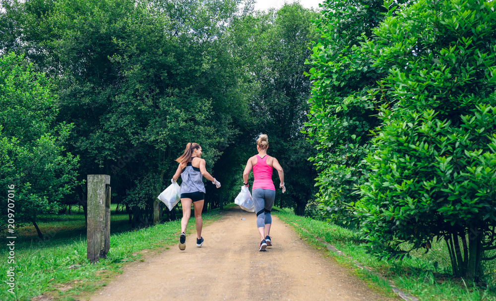 Fotografie Two girls on back with garbage bags doing plogging